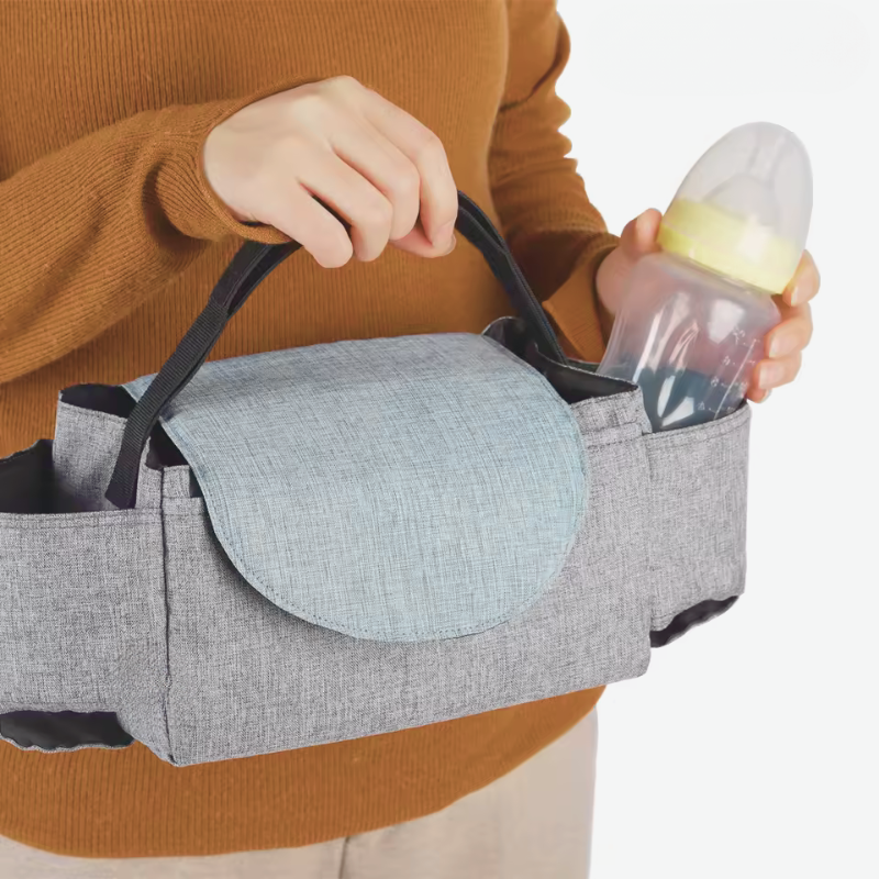 Person holding a baby bottle with a gray diaper bag on a white background